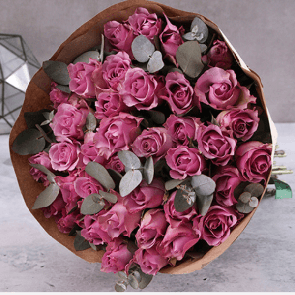 A stunning bouquet of 12 premium purple roses with eucalyptus leaves, perfect for gifting and flower delivery in Dubai.