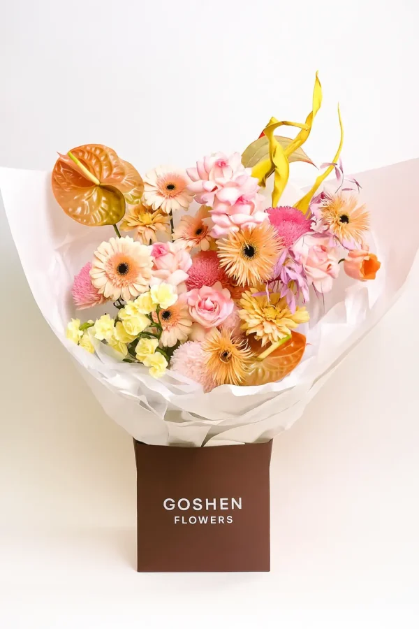 Golden hour glow flower bouquet with anthuriums, calla lilies, and greenery in a brown gift bag – Goshen Flower Dubai.